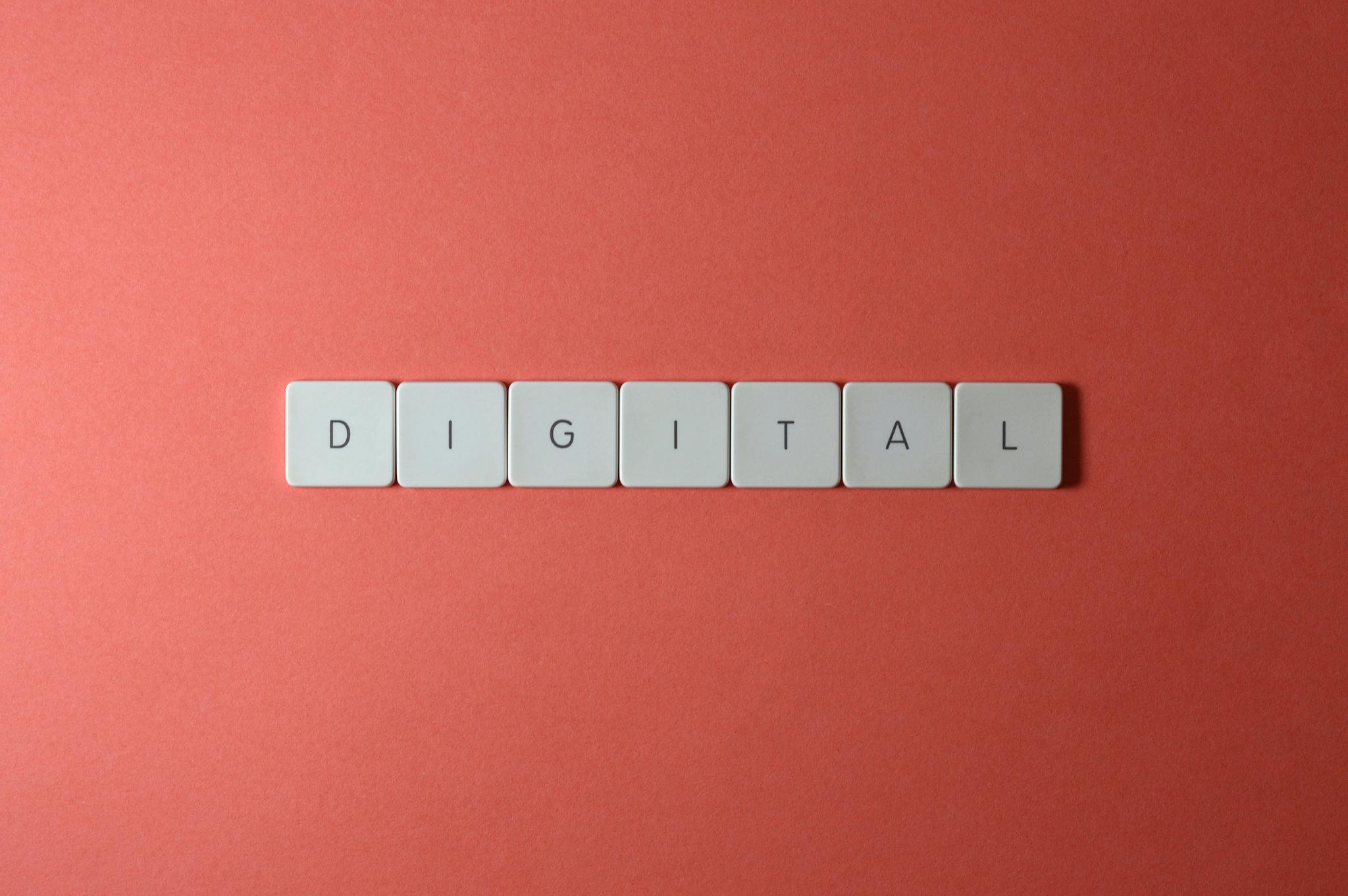 Close-up of keyboard tiles spelling 'DIGITAL' on a red background, perfect for tech themes.