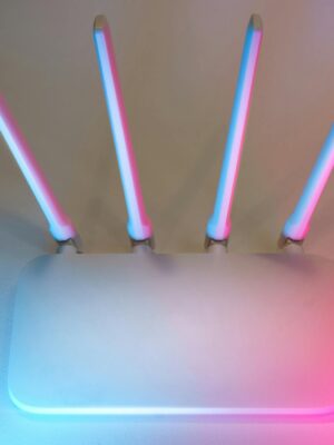 Sleek white wireless router with four antennas emitting soft blue and pink light.